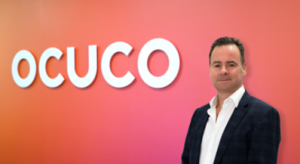 Leo Mac Canna in front of a sign that says 'Ocuco'.