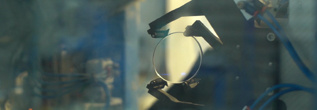Machine holding lens for inspection in an optical lab